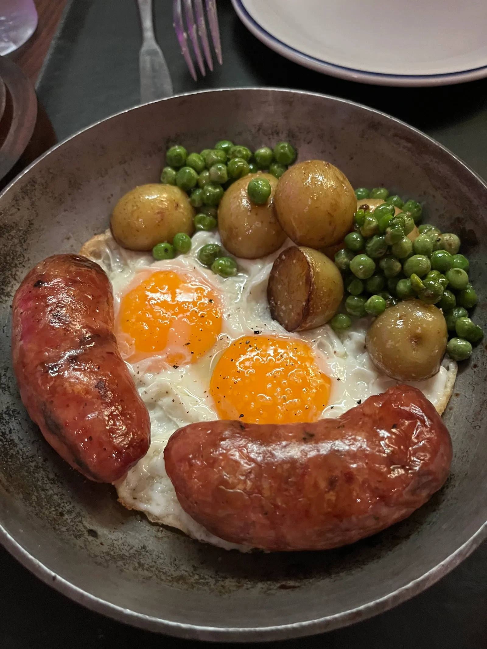 Chorizo casero con huevos, arvejas y papas doradas